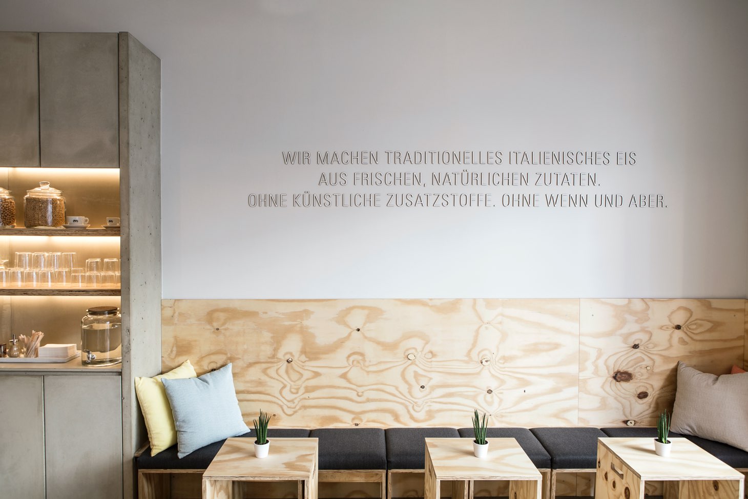 Leones Shop mit Firmenphilosophie als Wanddesign und Sitzgelegenheiten aus Holz