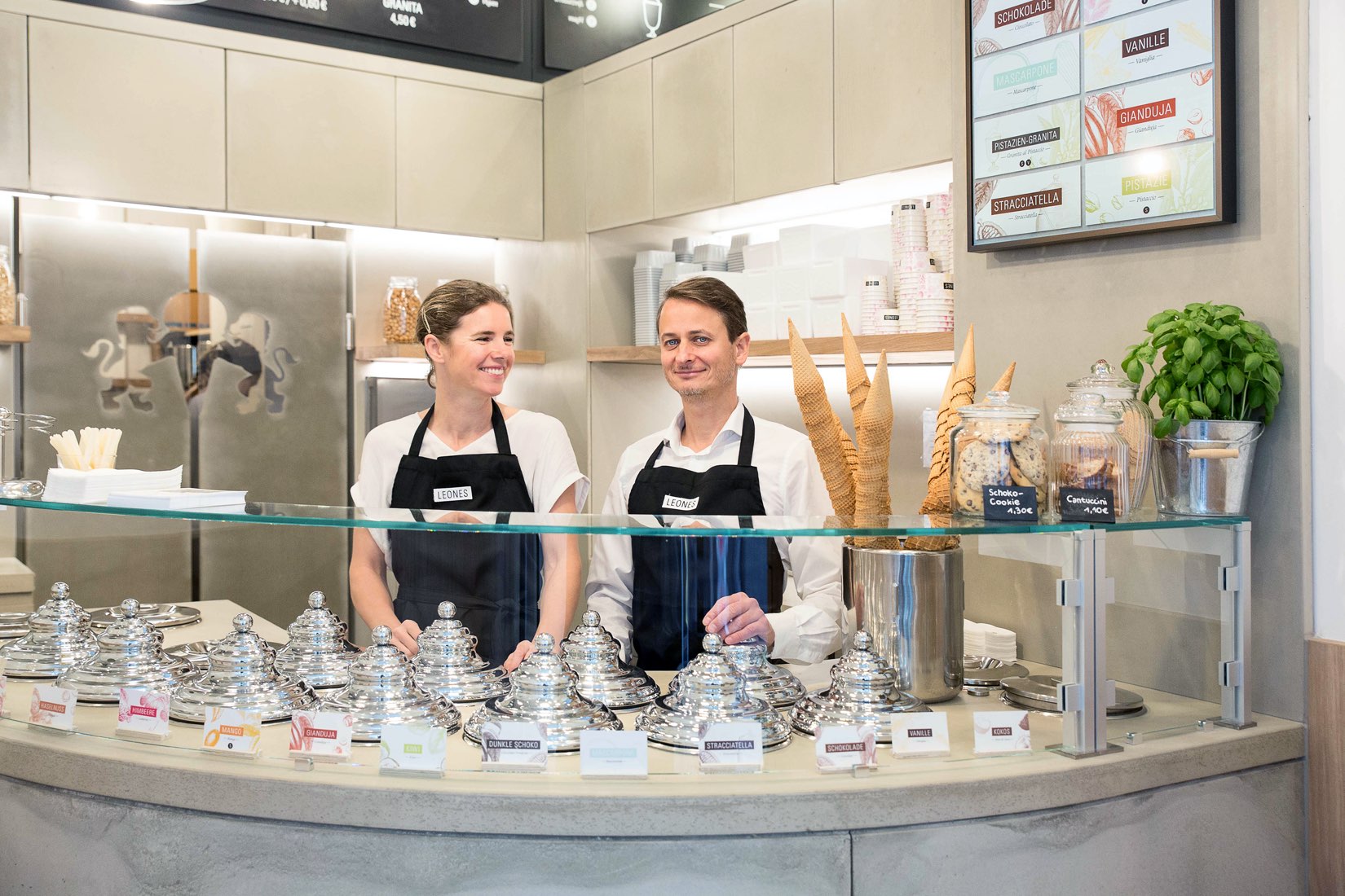 Lisa und Giorgio Leone im Leones Shop Freisingergasse mit runder Eistheke aus Beton und digitalem Sortenschild