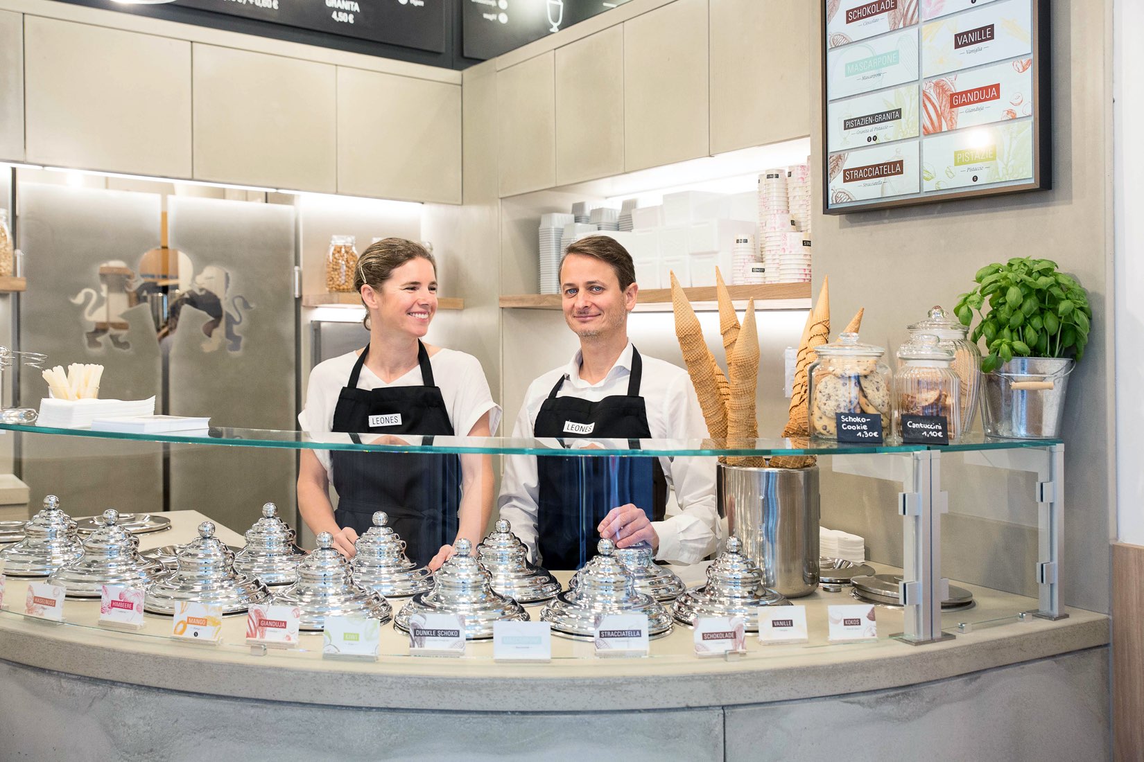 Lisa und Giorgio Leone im Leones Shop Freisingergasse mit runder Eistheke aus Beton und digitalem Sortenschild